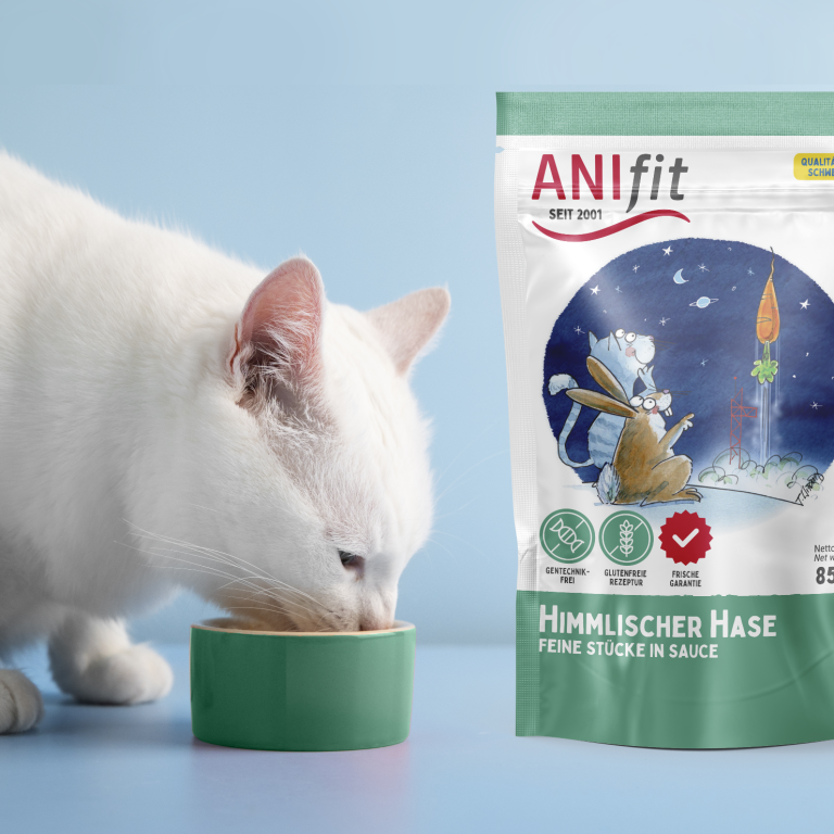 Weißer Kater frisst aus einer Schüssel neben einem Beutel ANIfit Katzenfutter.