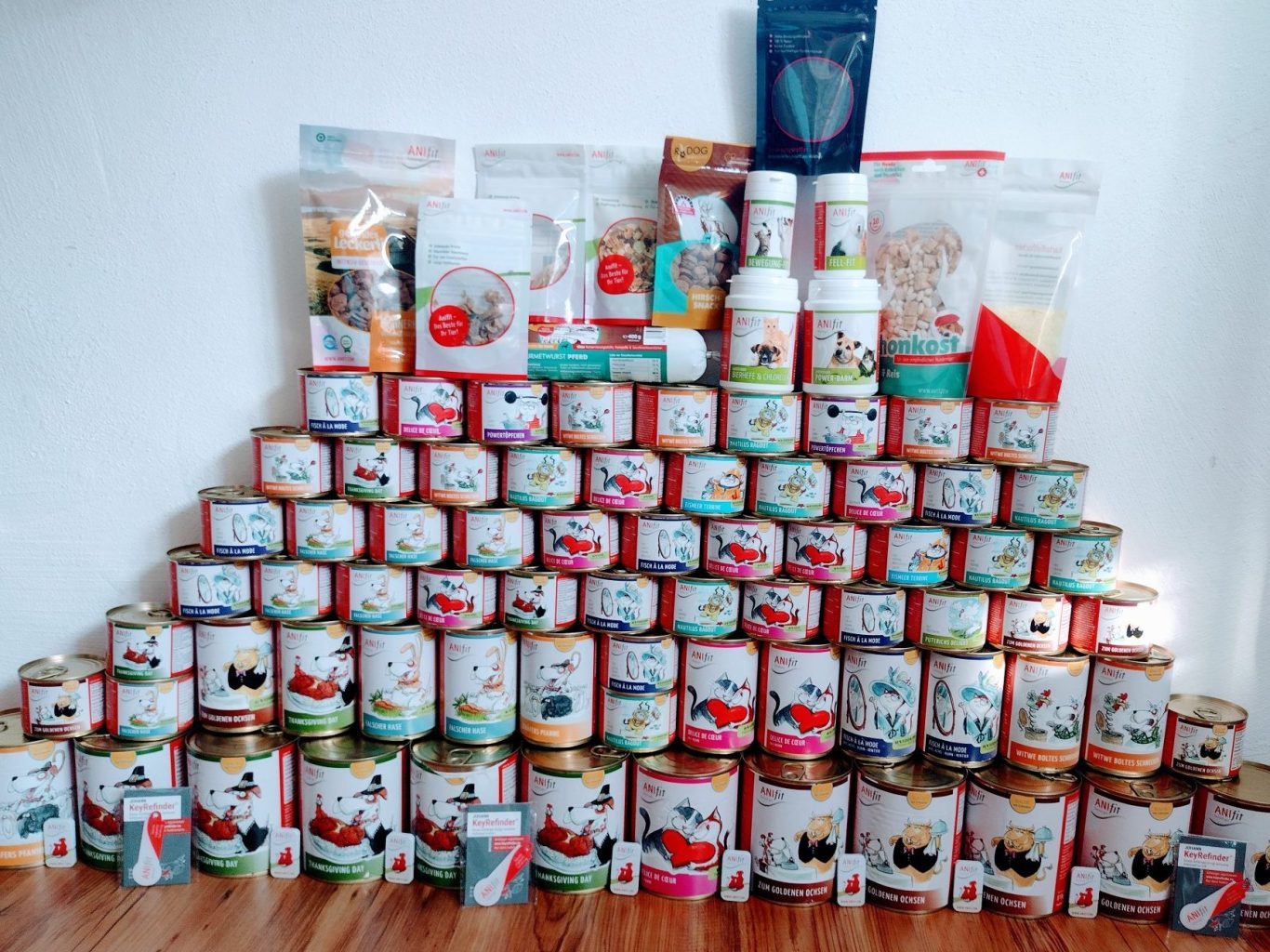 Verschiedene ANIfit Futterdosen und Snacks, aufgestapelt in einer ansprechenden Anordnung.