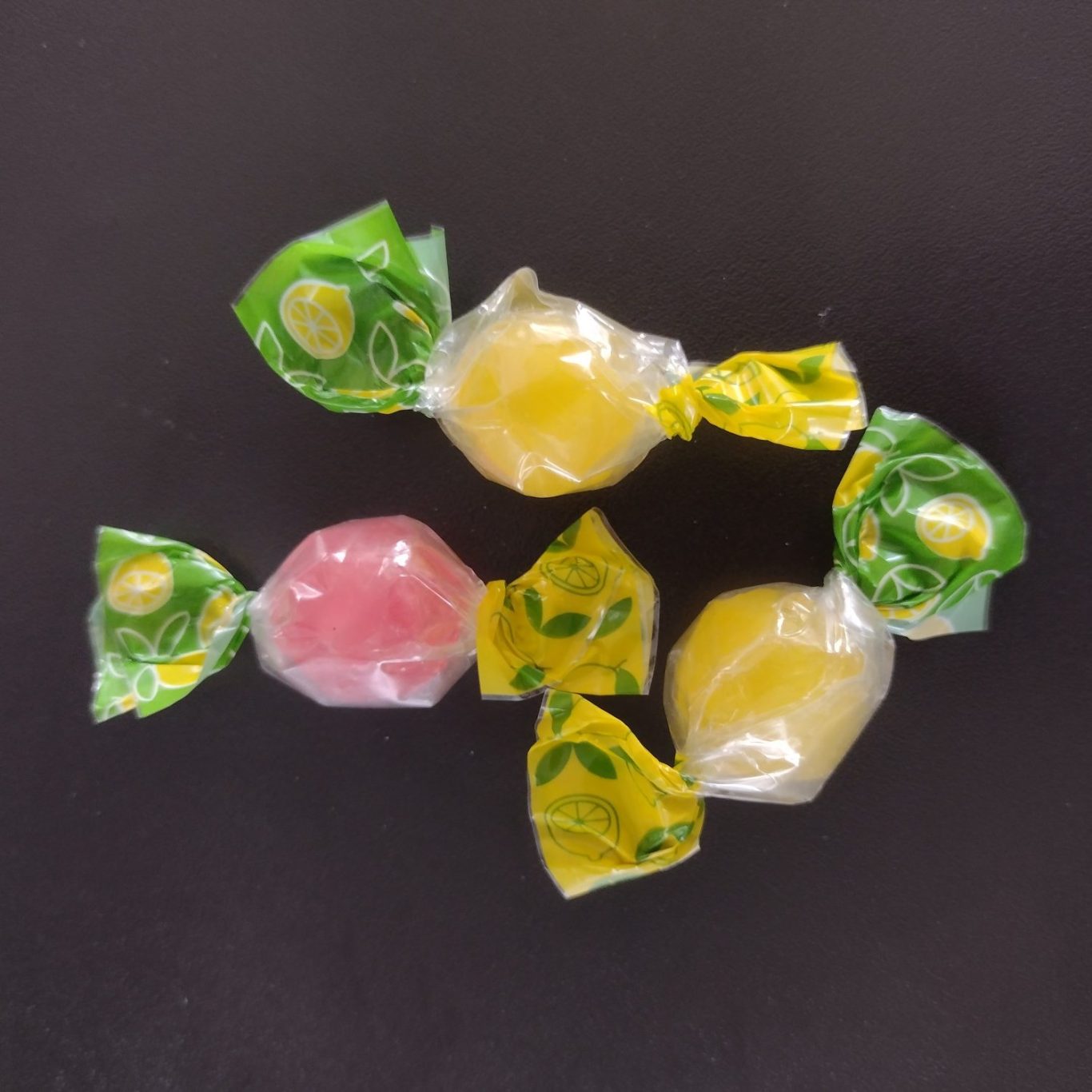 Bunte Fruchtbonbons in durchsichtiger Verpackung auf dunklem Hintergrund.