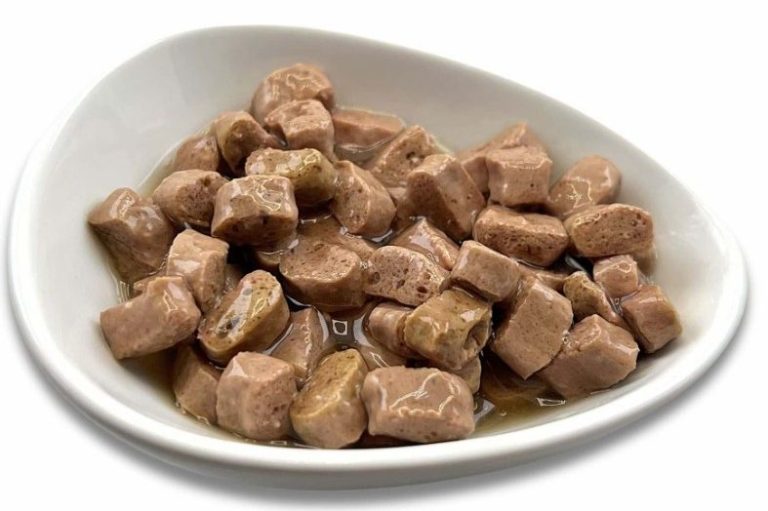 Hochwertiges Nassfutter für Katzen entdecken Schüssel mit kleinen Würfeln von Katzenfutter in brauner Soße.