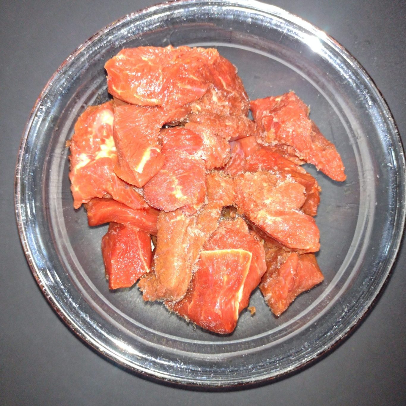 Schüssel mit mariniertem, gewürfeltem Fleisch in einem hellem Farbton.